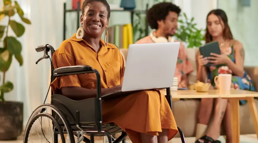 Woman in a wheelchair using a laptop while smiling