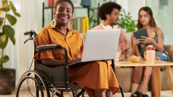 Woman in a wheelchair using a laptop while smiling