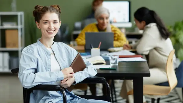Young woman in a wheelchair smiling in an office environment